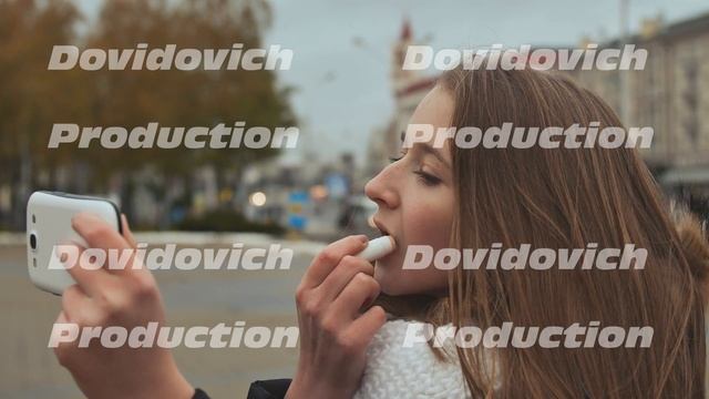 Young Beautiful Girl Lipstick Hygienic Lipstick On A City Street. Autumn. Cold