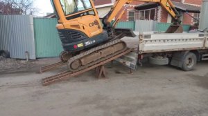 Мини экскаватор заезжает на грузовик.