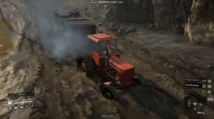 Трактор МТЗ 82 с прицепом едет через грязь