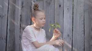 Young Teen Girl in Pink Dress Admires a Green Plant