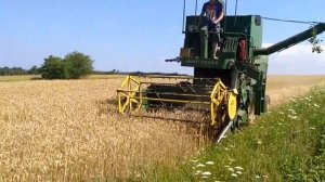 Комбайн Jonn Deere молотит пшеницу в поле,сбор урожая