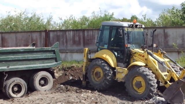 Экскаватор-погрузчик New Holland LB115 грузит самосвал КАМАЗ. смотреть онлайн