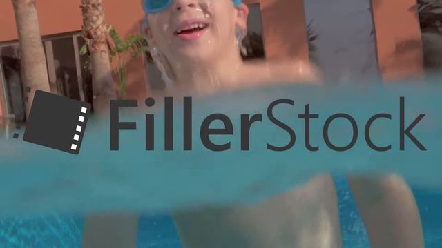 A slow motion of a boy diving in and out the open pool
