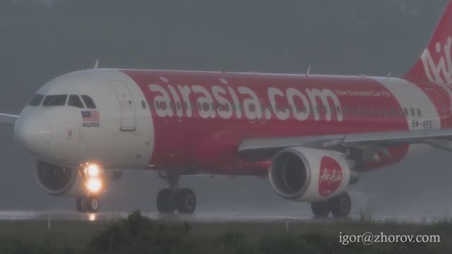 Эйрбас А320 авиакомпании AirAsia взлетает из аэропорта Куала Лумпура во время тропического ливня.