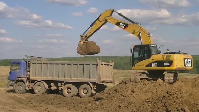 Экскаватор Cat 320D L грузит самосвалы Scania P380 и Volvo A30E