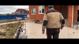 Пиленая гранитная брусчатка в частном доме . Бригада укладчиков тротуарной плитки . Мостовая ру .