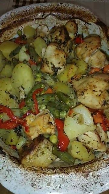 Запеченные овощи, картофель и куриное филе в керамической посуде.