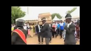 Негры несут гроб на плечах и танцют.