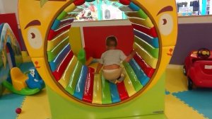 Ребенок катается с горки на детской площадке, прыгает