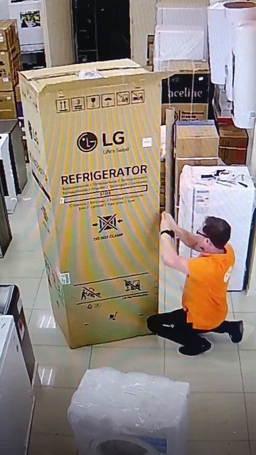 Сотрудник DNS распаковывает высокий холодильник LG