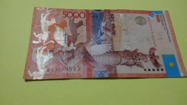 БАНКНОТА 5 000 ТЕНГЕ № серии ВК4074655 на жёлтой поверхности Одиннадцатого Января - ДЕНЕЖНЫЙ ПОТОК