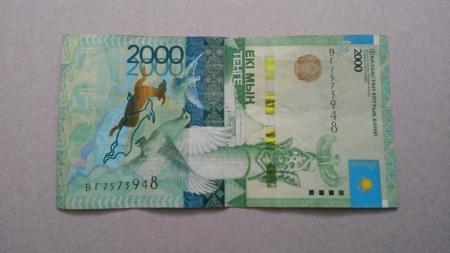 БАНКНОТА 2000 ТЕНГЕ № серии ВГ7573948 на картонной поверхности Двенадцатого Февраля - ДЕНЕЖНЫЙ ПОТО