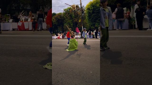 Мем Гном в зеленом плаще и с сачком на дне города