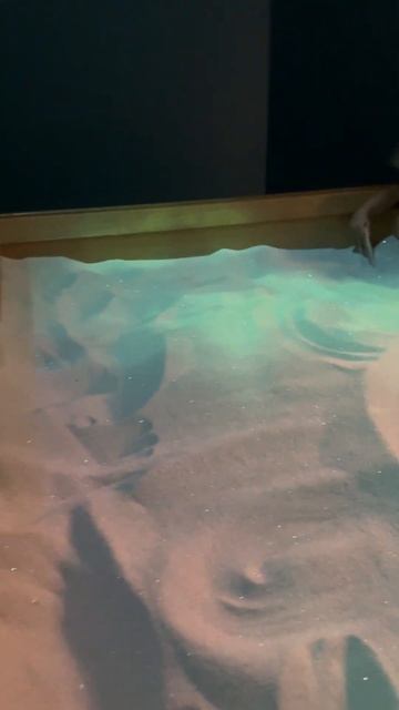 Дети играют с песком на выставке в музее. Короткое вид?