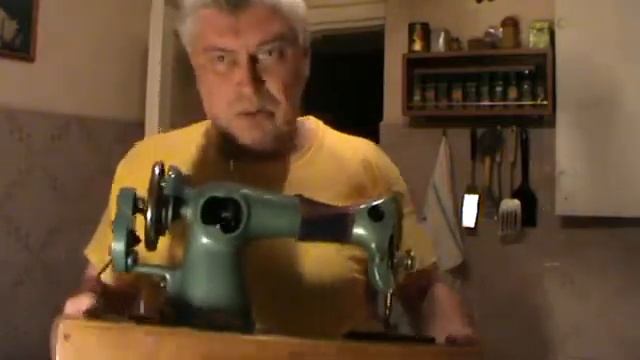 Мужик поднимает швейную машинку руками. Удаленное видео Геннадия Горина