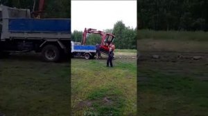 Съезд мини экскаватора с самосвала.