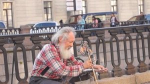 Петербургский дедушка музыкант играет на пиле