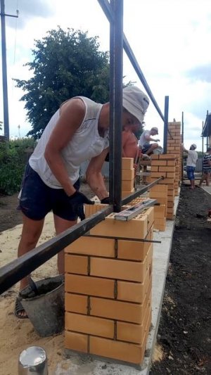 Хорошая работа! Каменщики строят кирпичные столбы для забора.