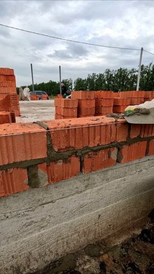 Мастер кладет стену из кирпичей.