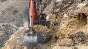 Экскаватор против массивной скалы.