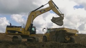 Экскаватор Cat 374D LME грузит самосвалы John Deere 400D