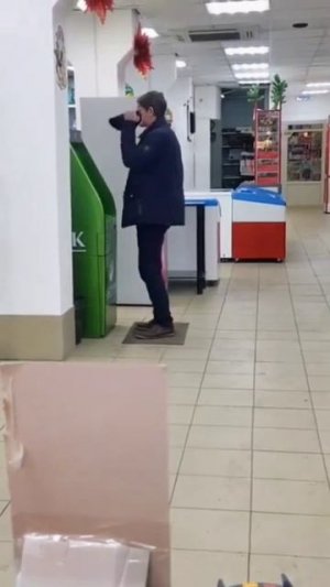 Мужчина стоит возле банкомата танцует