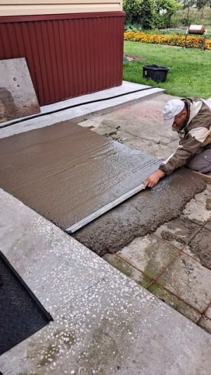 Мужик заливает во дворе бетон.