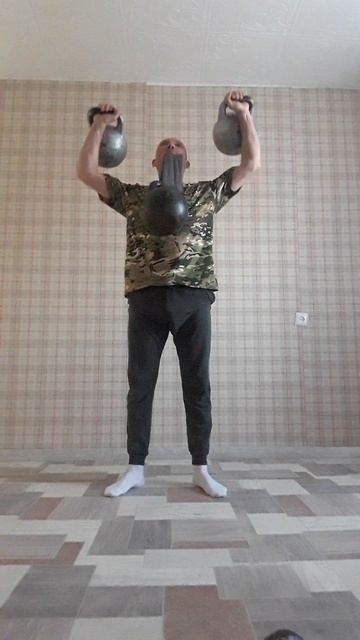 Гиря 24 кг. в зубах и две гири по 16 кг. в руках при выполнении силовой связки из упражнений.