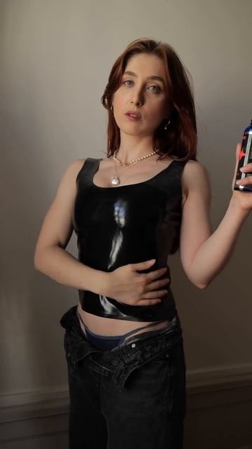 Девушка в латексе натирает себе полиролью  для блеска