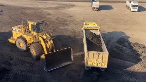 Погрузчик Caterpillar 990 загружает уголь в грузовики.