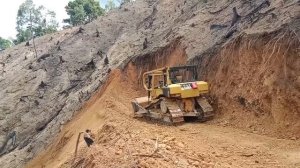 Бульдозер CAT D6R XL прокладывает дорогу на краю пропасти.