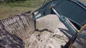 Экскаватор копает яму под водоем.