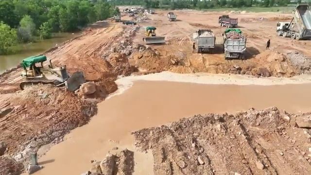 Бульдозеры толкают камни и почву, заполняя провалившуюся территорию с помощью сотни самосвалов. смотреть онлайн
