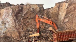 Экскаватор Hitachi рушит огромный холм.