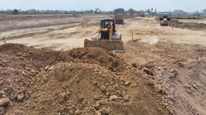 Экскаватор идёт на большой риск при строительстве канала — поддержка бульдозера и самосвала.