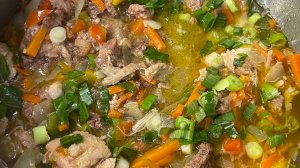 Гречка с овощами и тушенкой на плите.