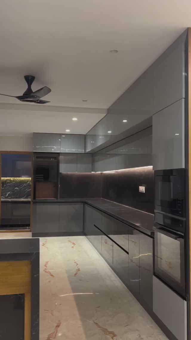 Кухня с лаконичными серыми фасадами и чёрной каменной столешницей