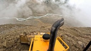 Бульдозер работает на склоне горы со страховочной лебедкой.