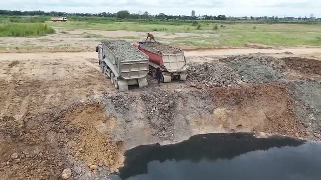 Отсыпка берега. Тяжелые самосвалы выгружают камень и грунт, а бульдозер продвигает их! смотреть онлайн