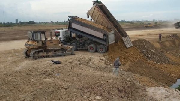 Komatsu D58 и грузовики отсыпают берег озера.