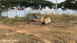 Бульдозер заполняет траншею травой.