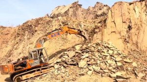Экскаватор уничтожает скалу.