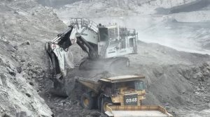 Большой экскаватор-погрузчик Liebherr R9350 загружает вскрышные породы на самосвал Caterpillar Cat