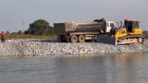 Замечательный бульдозер Shantui C3 сбрасывает породу в воду с помощью 25-тонных самосвалов , которые