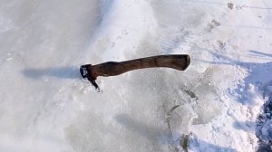 Топор с деревянной рукоятью, воткнутый в лед