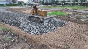 Строительство дороги. Бульдозеры разравнивают камни, которые привозят самосвалами