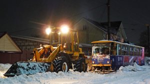 Вагон трамвая  тянут погрузчиком по заснеженной линии