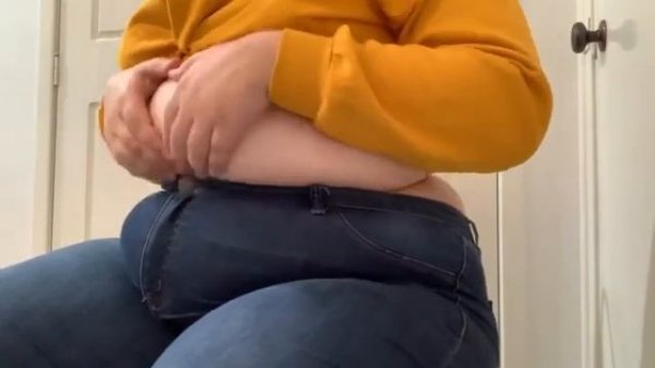 девушка играет с круглым животиком в джинсах