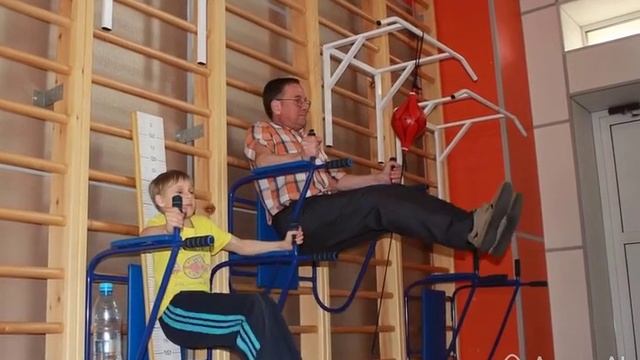 Отец с сыном занимаются физкультурой в школьном спортзале
