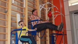 Отец с сыном занимаются физкультурой в школьном спортзале